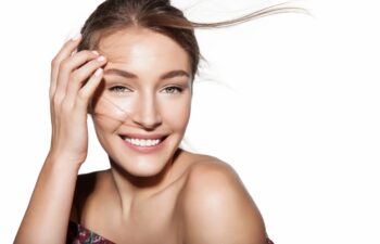 Beautiful woman portrait with hair flies. Female face close up studio portrait, isolated on white. Girl with clean skin and fresh daily make-up. Concept of cosmetology and beauty industry.